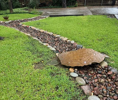 Drainage bed with rock beside a wooden deck